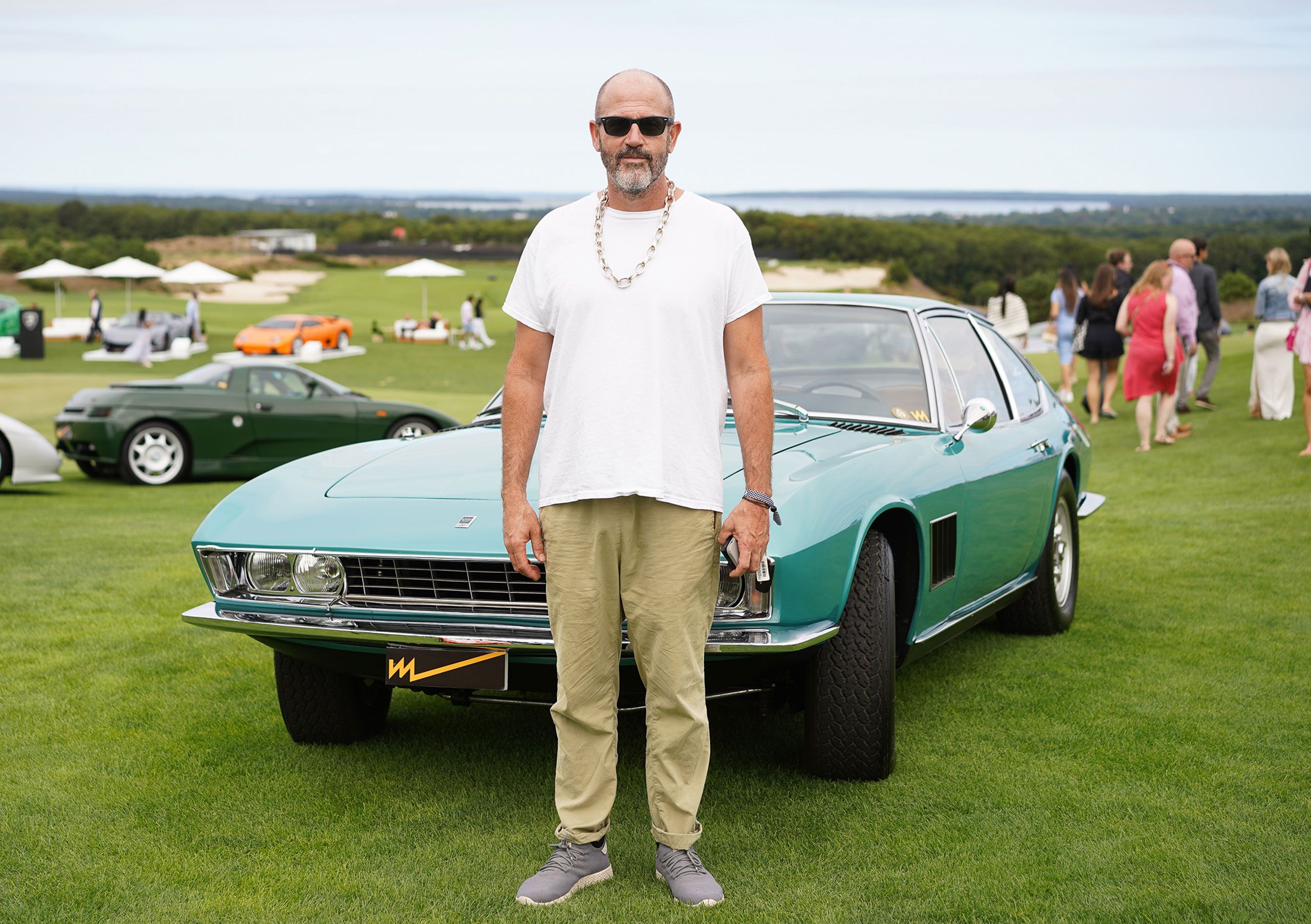 James Frey stands in front of a green car. Hes wearing white Tshirt khaki trousers and sneakers.